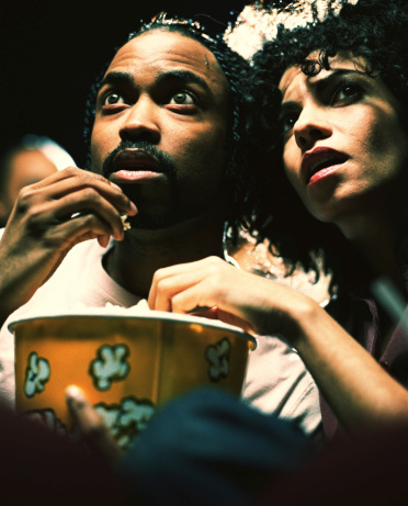 Man and woman in theater eating popcorn