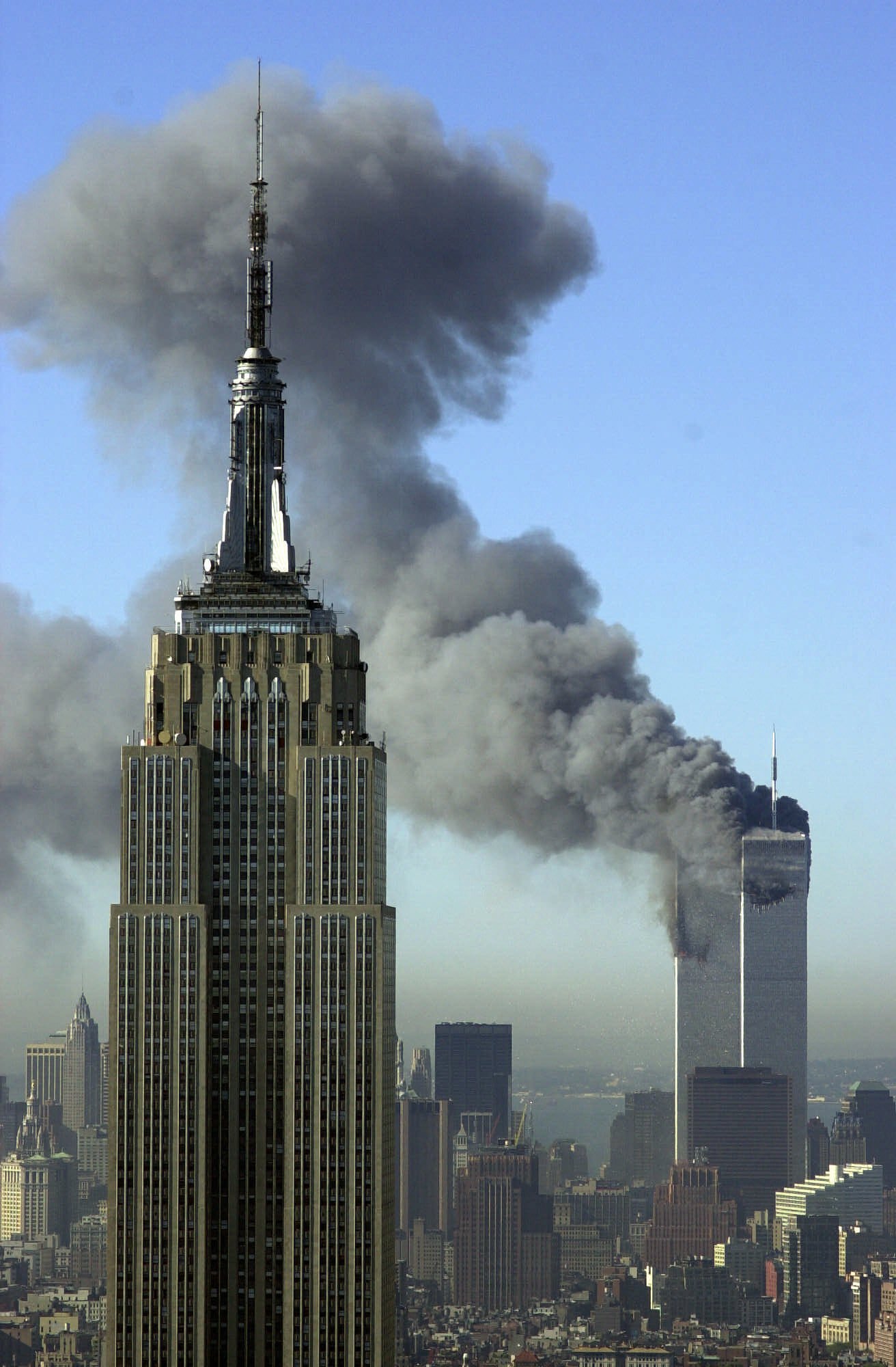 Plumes of smoke pour from the World Trade Center buildings in New York Tuesday, Sept. 11, 2001. Planes crashed into the upper floors of both World Trade Center towers minutes apart Tuesday in a horrific scene of explosions and fires that lead to the collapse of the 110-story buildings. The Empire State building is seen in the foreground. (AP Photo/Patrick Sison)
