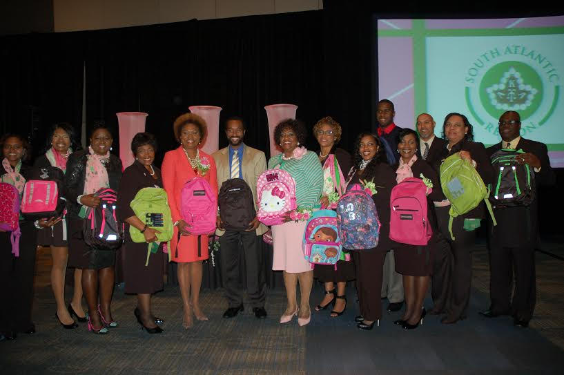 Pictured: Center Right: SA Regional Director Sharon Brown Harriott and Center Left: Cluster V Coordinator Shevawn Broxton Young along with the SA Region International Program Committee Representative Thuane B. Fielding (to right of Regional Director); Upsilon Alpha Omega and Tau Pi Chapter leadership;and Upsilon Alpha Omega Cluster V Conference leadership donate 500 backpacks to Graves Elementary, Representatives of the school including Graves Elementary Principal Clayborn Knight at CENTER, were on hand.