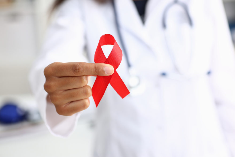 Black woman doctor holding a red ribbon