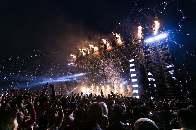 Concert attendees fill the crowd and blue lights strobe across the stage.